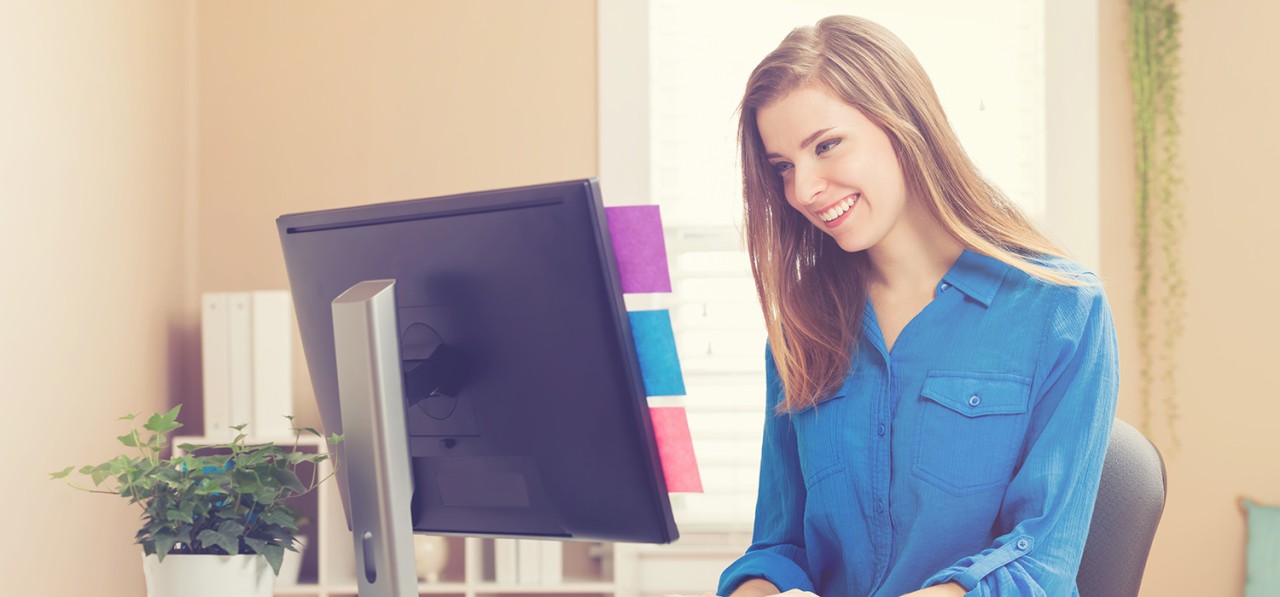 happy-young-woman-using-her-computer-in-her-home-office-SBI-317520857